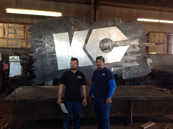 Two men standing in front of KC logo